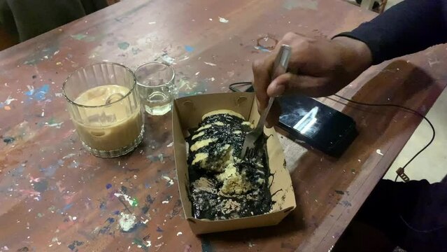 Footage A man is cutting cubit cake using a fork