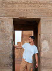 young male traveler visits Kom Ombo Temple at sunset. Egypt.  - obrazy, fototapety, plakaty