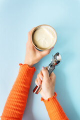 The girl holds in her hands creamy ice cream in a craft bucket. Ice cream spoon. Blue background, copy space.