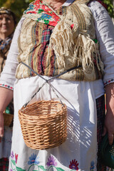 Wicker basket for picking berries on the belt of an elderly woman in folk costume.