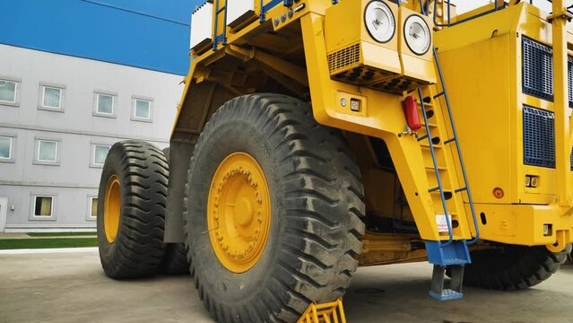 Big dump truck in a coal mine. A large dump truck standing by the factory walls. Yellow quarry truck. Close-up. Panorama from the bottom up