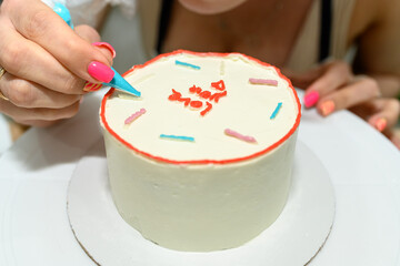 Fototapeta na wymiar Manicured female hands decorate a chocolate cake. Sweet dessert.