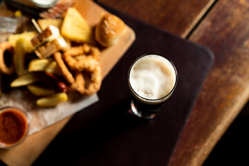 Overhead view of beer glass with snacks in the pub