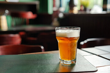 Ice Cold Glass of Beer on the table. Pub in the background
