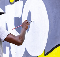A determined young artist working tirelessly on a mural that tells a powerful story, using their art to raise awareness and inspire change in the community.