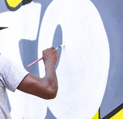A determined young artist working tirelessly on a mural that tells a powerful story, using their art to raise awareness and inspire change in the community.