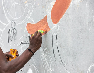 A young artist passionately painting a vibrant mural on a city wall, adding a burst of color to the urban landscape.
