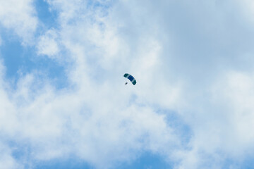 A parachutist in a blue sky under the clouds.