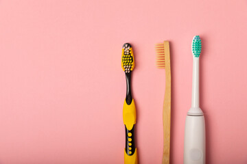 electric toothbrush, bamboo and handmade toothbrushes on a pink background with copy space. Flat lay. Oral hygiene. Oral care kit. Dentist concept. Place for text. Place to copy.