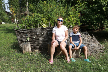 Mother with her son sitting on stump in backyard