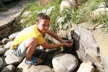 Naklejka na ściany i meble Child washing his hands in stream