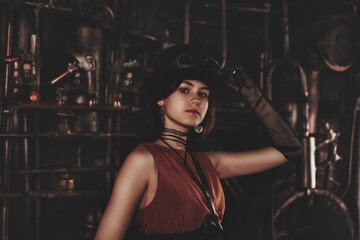 Classy teen girl model in steampunk image in retro brown dress and top hat looking at camera. Toned...