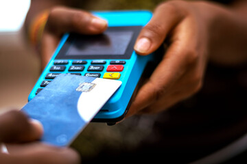 A person holding a credit card making payment with pos machine