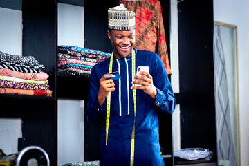 Photo of a black african man using a smartphone while standing in front of a wardrobe