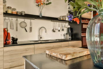 a kitchen with pots and uts hanging on the wall next to a vase filled with colorful flowers in it