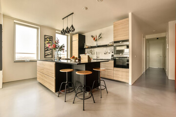 a kitchen with two stools in the middle and an orange door leading to the living room on the right