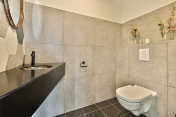 a bathroom with a toilet, sink and flowers in vases on the wall next to the toilet is black
