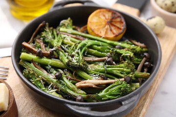 Tasty cooked broccolini, mushrooms and lemon on board, closeup