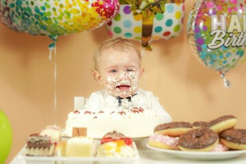 A small child with a smeared face in a cake is crying.