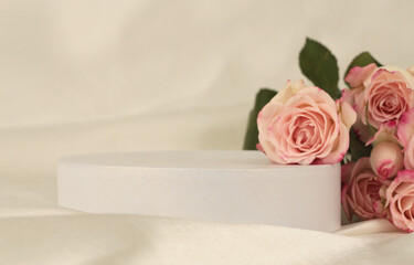 Fototapeta premium Pink rose flower bouquet on white podium and silk fabric.. Light beige background. Minimal empty display product presentation scene.