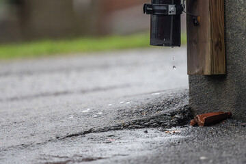 Rain water dropping from a pipe on a wall.