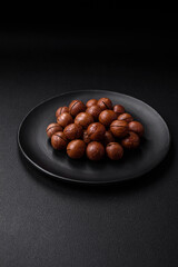Delicious roasted macadamia nuts in shell on a dark textured background