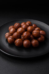 Delicious roasted macadamia nuts in shell on a dark textured background