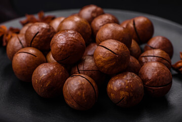 Delicious roasted macadamia nuts in shell on a dark textured background