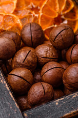 Delicious roasted macadamia nuts in shell on a dark textured background