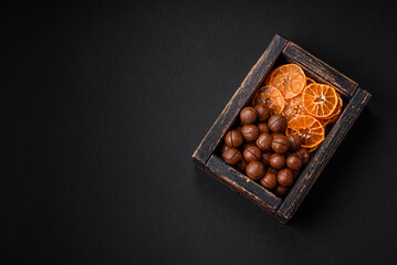 Delicious roasted macadamia nuts in shell on a dark textured background