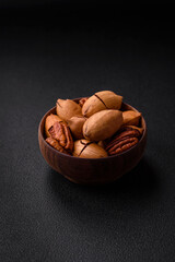 Pecan nuts in shell and peeled in a wooden round bowl