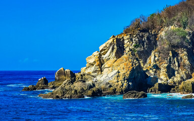 Surfer waves turquoise blue water rocks cliffs boulders Puerto Escondido.