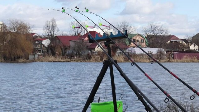 Three fishing rods are fixed on the holder and installed on the shore of a lake or river with signaling devices. Feeder fishing. Catching carp, silver carp, tench and other peaceful fish.