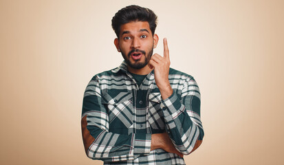 Eureka. Inspired young indian man pointing finger up with open mouth, having good idea, plan,...
