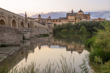 Fototapeta na wymiar Roman bridge of and the Mosque–Cathedral of Cordoba. Exposure at sunset of the Roman bridge of and the Mosque–Cathedral of Cordoba in the background with the Guadalquivir river in the foreground