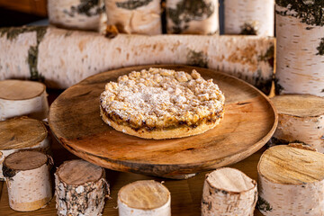 Rhabarberkuchen, Sträußelkuchen auf Holztablett umringt von Birkenstämmen als Dekoration