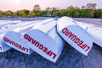 lifeguard skiffs, freshly painted, turned hull side up on a beach waiting for the warm weather and...