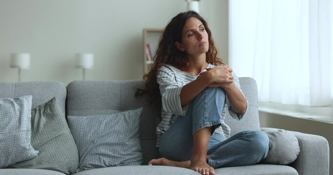 Young woman rest in living room looks deep in thoughts, having daytime rest, renewing energy, relax on comfortable couch, chilling alone on weekend leisure at home, have melancholic mood, feels bored