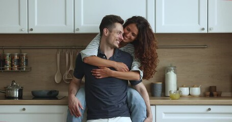 Beautiful Latina wife sit in kitchen countertop hugs with love and tenderness handsome Latin husband. Young family enjoy love, harmonic relationships, spend romantic dating at home. Tenancy, new house