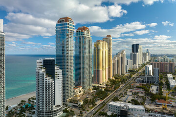Obraz premium View from above of luxurious highrise hotels and condos on Atlantic ocean shore in Sunny Isles Beach city. Urban street with busy traffic. American tourism infrastructure in southern Florida