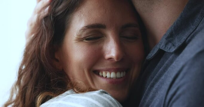 Close up face of beautiful serene Hispanic woman enjoy cuddles, snuggles to her beloved man, his hand strokes her head with tenderness, showing love, gives protection and support. Relations, harmony