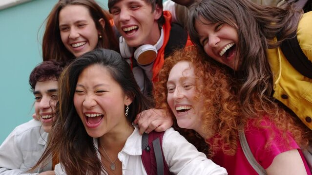 Happy young group of college erasmus students laughing together outdoors. Millennial people from different cultures enjoying time together at university campus. Youth community and friendship concept.