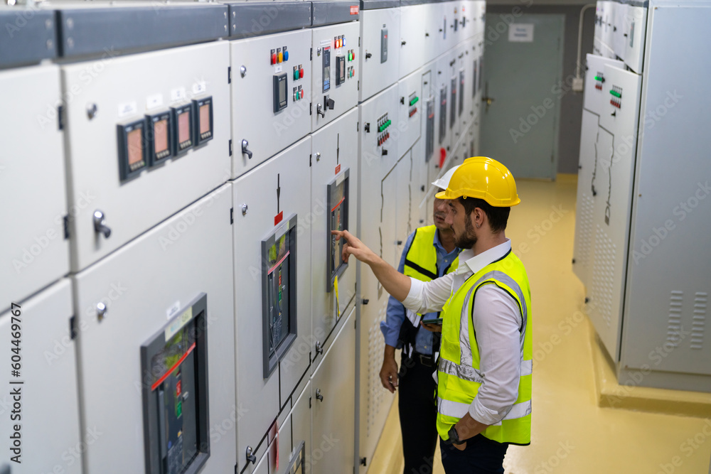 Wall mural professional electrical engineer in safety uniform working at factory server electric control panel 