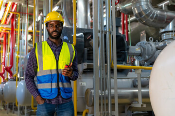 Portrait of Professional male electrical engineer in safety uniform working at factory site control room. Industrial technician worker checking and maintenance manufacturing power system at plant room