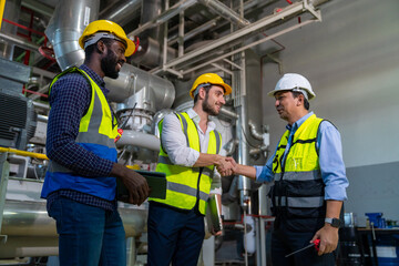 Group of Diversity electrical engineer in safety uniform working together at factory site control room. Industrial technician worker maintenance and checking power system at manufacturing plant room.