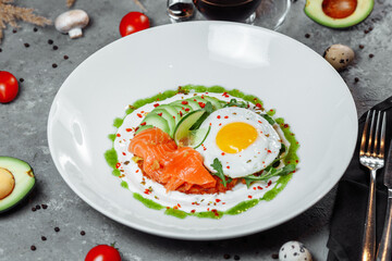 Poached eggs on top of smashed avocado on sourdough toast with smoked salmon. Healthy breakfast with plate on table. Top view. Copy space to right