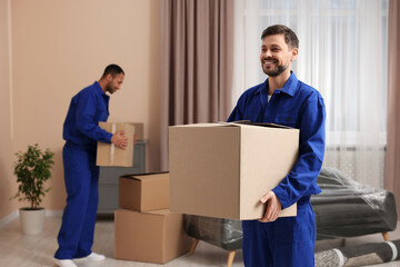 Male movers with cardboard boxes in new house