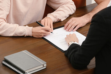 Obraz premium Notary helping couple with paperwork at wooden table, closeup