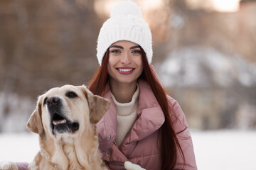 Beautiful young woman with adorable Labrador Retriever on winter day outdoors