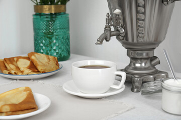 Vintage samovar, cup of hot drink and snacks served on table. Traditional Russian tea ceremony